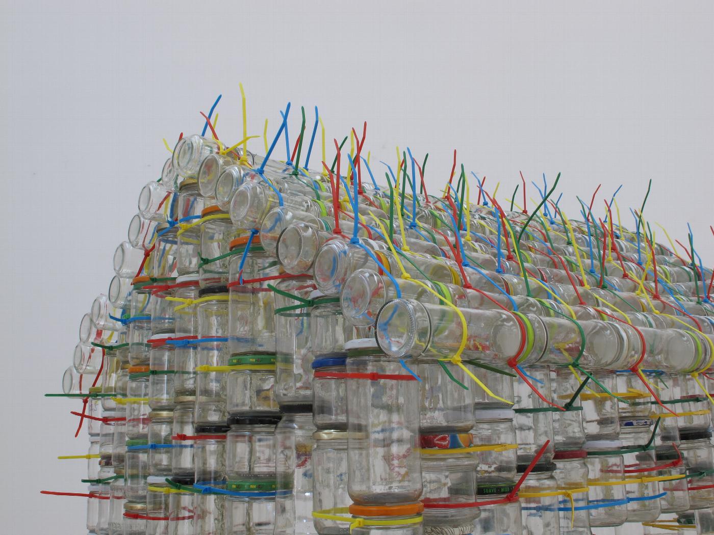 Escultura de Carmen Marcos (2009-2012) realizada con botes de vidrio reciclados que habla de las acrobacias familiares para llegar a fin de mes y pone en valor el reciclaje